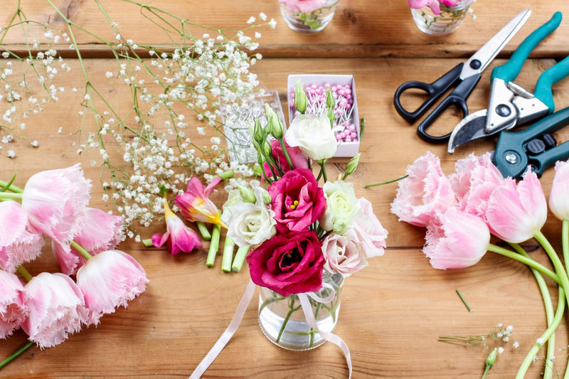 Florist workbench with stems, shears and a small glass vase