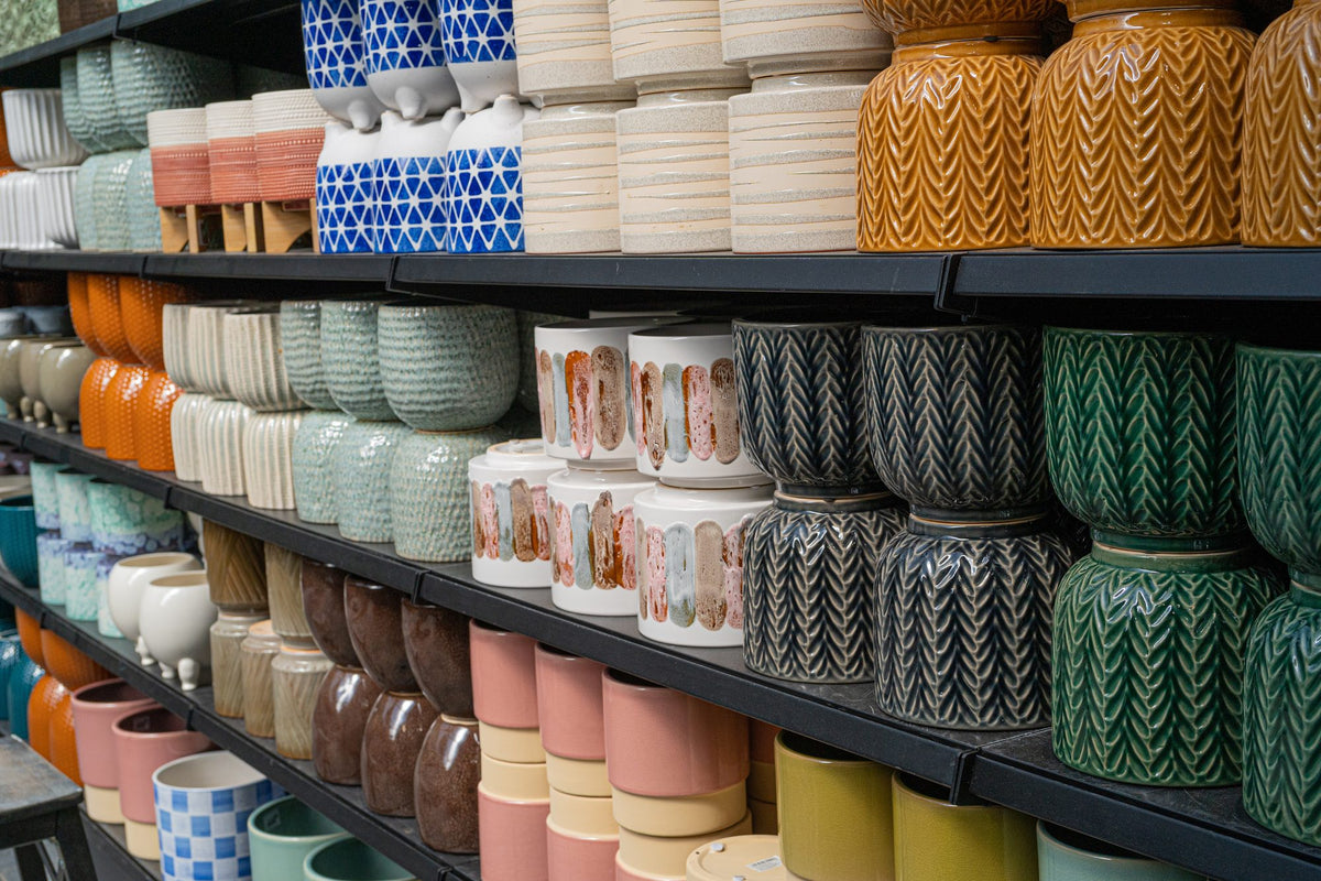 Ceramic pots and vases in assorted colors stocked on wholesale warehouse shelves