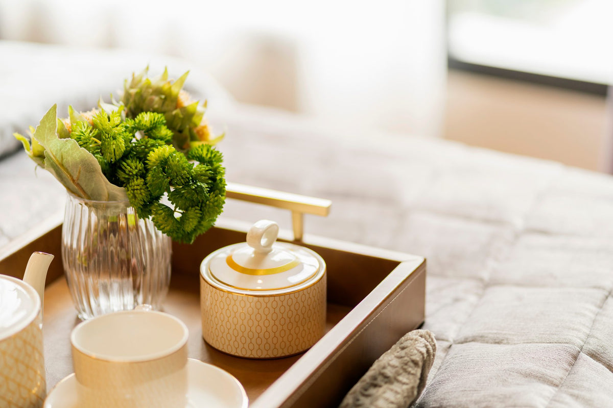 Staged side table with a wooden tray, a small glass vase of greenery and ceramic accents